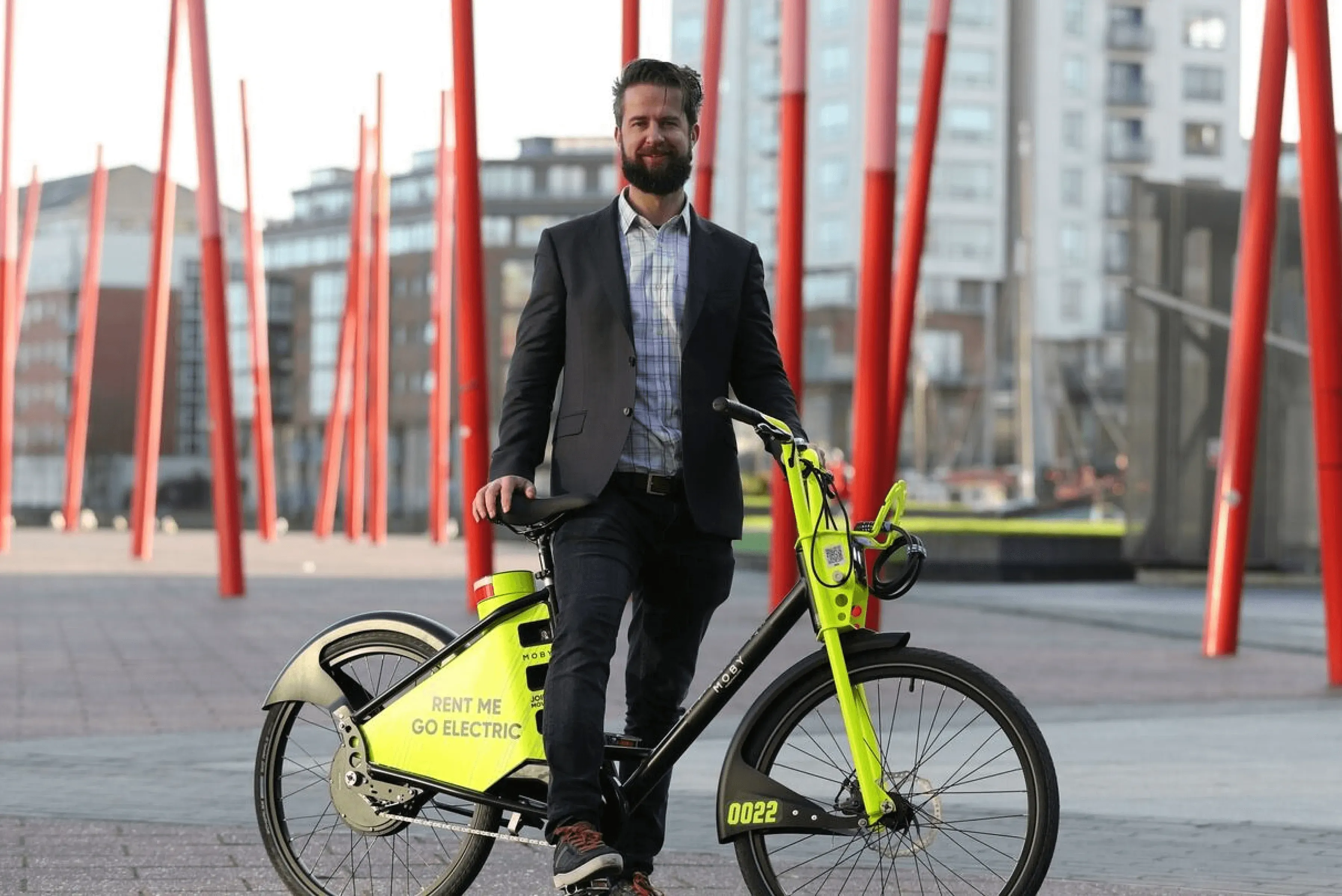 A professional stands with a bright yellow electric bike labeled 'Rent Me Go Electric,' highlighting CT Mobility's tailored e-bike solutions for London and Rotterdam operations
