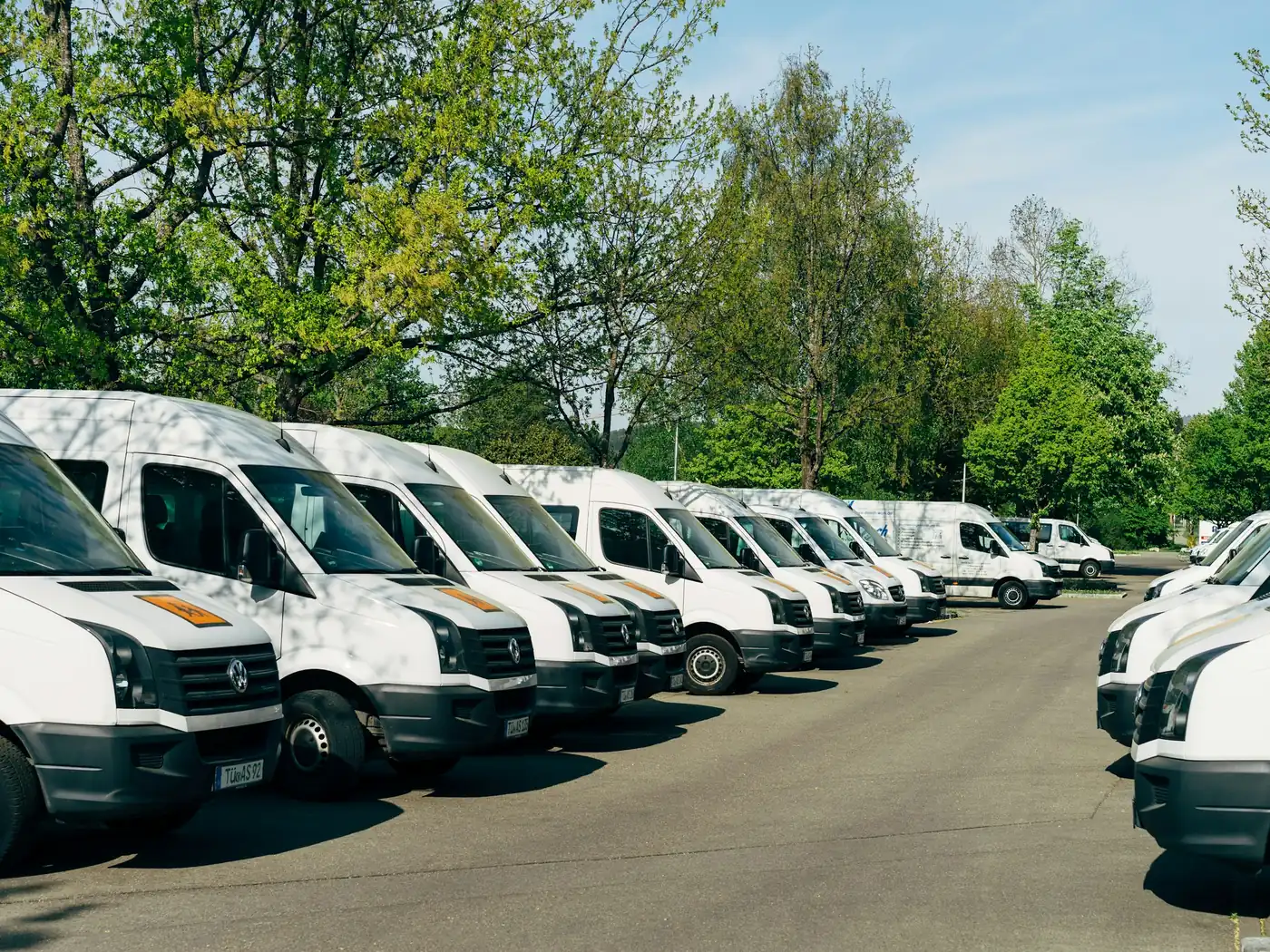 Long row of white company vans in a fleet car park